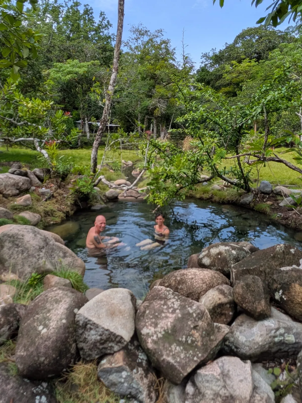 Bathers in a mossy, forest-shaded hot spring pool near Caldera